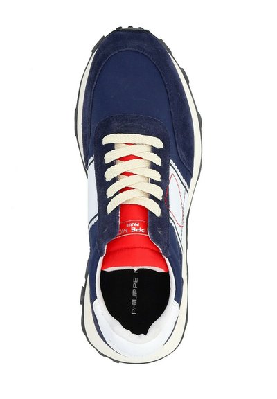 Baskets de sport bleu marine avec tige en suede et tissu, lacets crème, accents rouges et un logo blanc. Semelle extérieure en caoutchouc noir avec un motif de semelle.