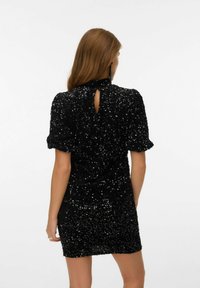 Melnas sekvīrām kleitas ar īsām, pūkām piedurknēm. Tam ir augsta kakla izgriezums un atvērtā vieta aizmugurē. Pieguļošs siluets, teksturēta auduma.