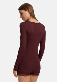 Bordowa bluzka z długim rękawem o dopasowanym kroju, z prążkowaną teksturą i okrągłym dekoltem, zestawiona z dopasowanymi szortami z koronkowym wykończeniem.