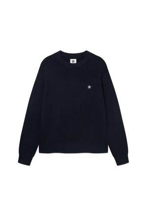 Pull en maille bleu marine foncé à manches longues, col rond et petit emblème blanc sur la poitrine gauche, présenté sur fond blanc.