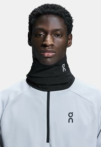 Black neck gaiter paired with a light gray athletic top featuring a textured pattern and a zippered collar. Logo printed on fabric.