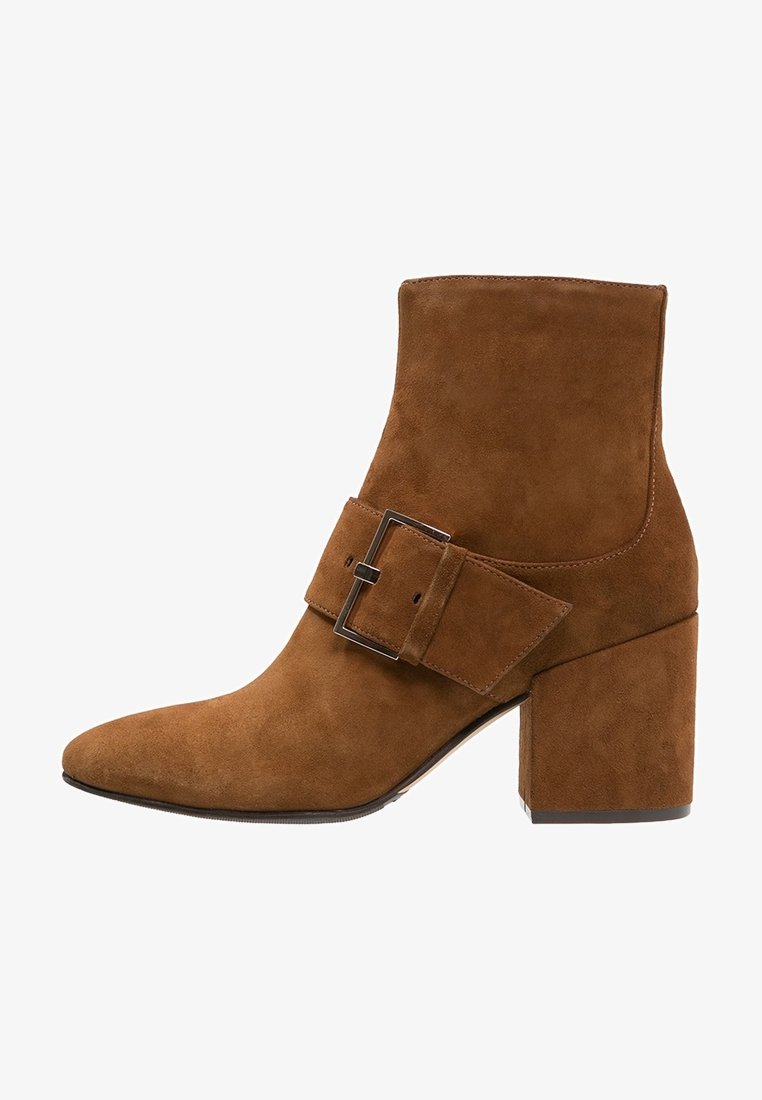 Bottine en daim marron avec talon bloc et grande bride à boucle sur le côté.