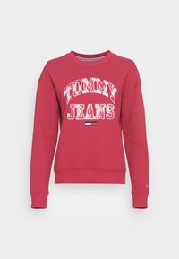 Červená mikina z bavlny s bílým nápisem "TOMMY JEANS" a malým trojbarevným logem na lemu. Zescofované manžety a výstřih.