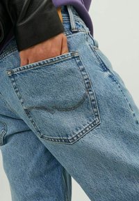 Ljusblå denimjeans med en synlig bakficka som har en böjd sömdetalj. Materialet är något urtvättat med en texturerad yta.