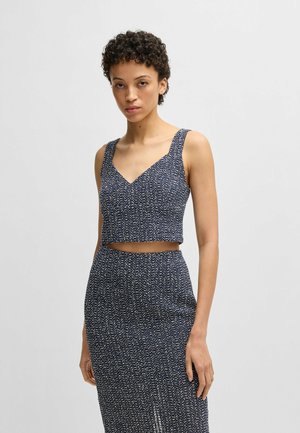 Top blu navy a maniche larghe, con un motivo tessuto a trama. Scollatura a forma di V. Abbinato a una gonna attillata coordinata, anch'essa a trama.