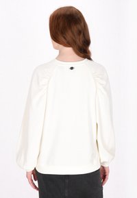 Witte pullover sweatshirt met gathering bij de mouwen, ribgebreide manchetten en een zwarte ronde detail aan de achterkant van de hals. Zachte textuur, comfortabele pasvorm.