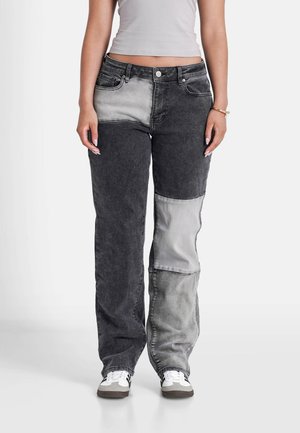 Vaqueros de denim en negro y gris con un diseño de pierna recta. Presentan un cierre de botón, cinco bolsillos y texturas de tela contrastantes.