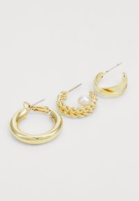 Três pares de brincos de ouro: um grande argola, um design torcido com uma pérola, e um estilo espiral fino. Acabamento metálico suave.