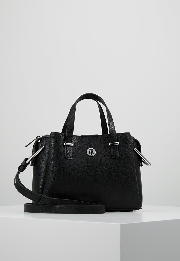 Musta nahkalaukku, jossa on teksturoitu pinta, kaksoiskahvat ja irrotettava olkahihna. Varustettu hopeisella logolla ja metallisilla yksityiskohdilla.