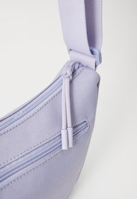 Borsa a tracolla lilla chiaro con tessuto testurizzato, caratterizzata da due tasche con zip e zip coordinati. Tracolla regolabile per maggiore comodità.