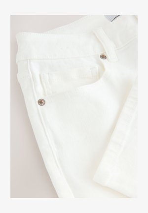 Valge puuvillast teksapüksid, millel on tekstureeritud pind, tavaline vöökoht ja tagatasku metallilise aktsendiga.