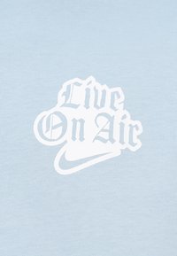 Ανοιχτό μπλε βαμβακερό t-shirt με λευκό τυπωμένο κείμενο "Live On Air" σε στυλιζαρισμένη γραμματοσειρά και λογότυπο Nike από κάτω.