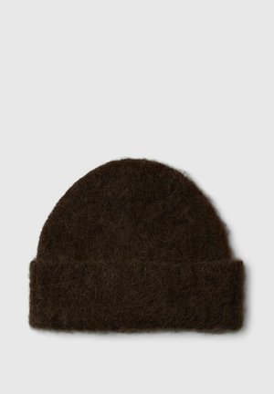 Gorro de punto peludo marrón oscuro con puño doblado sobre un fondo claro y liso.