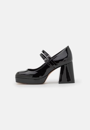Sort patentlæder Mary Jane-sko med dobbelte remme, lav platform og chunky blokhæl, vist i sidet profil på hvid baggrund.