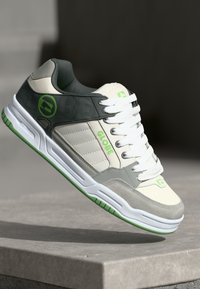 Gray and cream sneaker with white laces and green accents. Features a rubber sole, suede and synthetic materials, and a logo on the side.