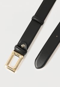 Cintura nera in pelle con fibbia rettangolare dorata, cuciture visibili e due passanti, su sfondo bianco.