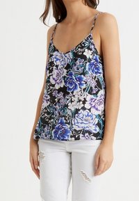 Svart blommig linne med justerbara spaghetti-band, dekorerat med blå och lila blommor på en kontrasterande bakgrund. Bärs med vita utslitna byxor.