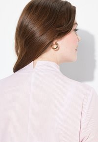 Blusa a strisce rosa chiaro e bianco con colletto alto, caratterizzata da una apertura a forma di chiave sul retro e una texture di tessuto liscia.