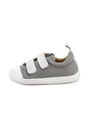Zapatilla de lona gris con punta y suelas de goma blanca, que presenta dos correas de velcro y un material superior texturizado.