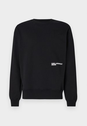 Svart genser med rund hals, lange ermer og ribbestrikkede mansjetter. Har hvit "KARL LAGERFELD JEANS" logo på venstre bryst.