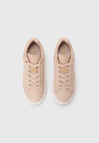 Pair of beige low-top sneakers with laces and gold MK logo detail on a white background, viewed from above.