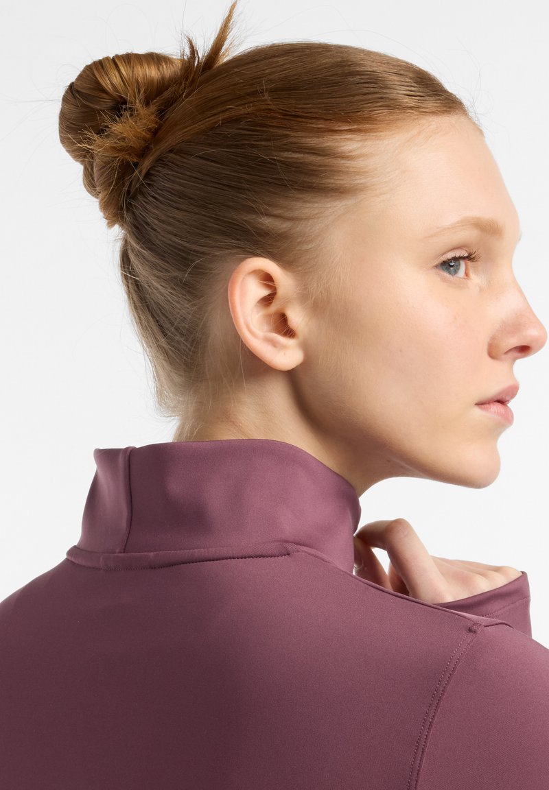 Prenda de manga larga en color ciruela, con un cuello alto y una tela suave y elástica. Primer plano del cuello y perfil lateral que muestra los detalles de la costura.