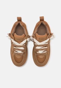 Braune Sneaker aus Wildleder und Mesh mit weißen Schnürsenkeln. Sie besitzen strukturierte Einsätze und eine kleine Fersenschlaufe hinten.