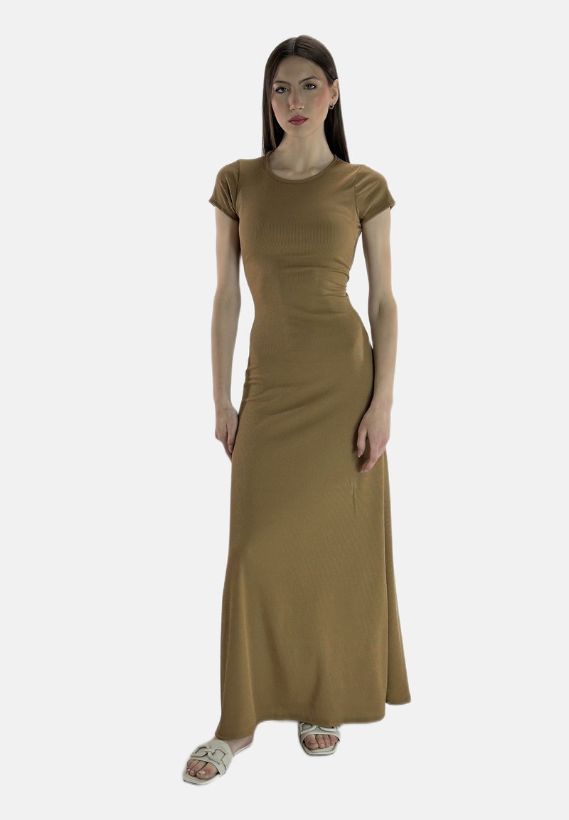 Robe maxi marron à côtes avec des manches courtes et une silhouette ajustée. Texture lisse et design minimaliste. Portée avec des sandales de couleur claire.