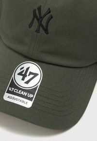 Olivno zelena bejzbolska kapa z črnim vezenim logotipom in nastavljivim trakom. Ima teksturirano blago in krožno oznako blagovne znamke.