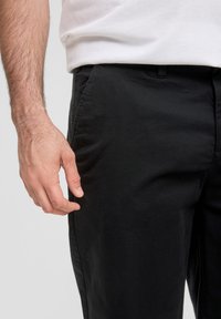Zwarte katoenen broek met een gladde textuur, zijzakken en een recht model, gecombineerd met een witte T-shirt met ronde hals.
