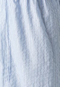 Tissu bleu clair avec des rayures verticales blanches et argentées. La texture semble lisse, avec un léger éclat et une légère transparence par endroits.
