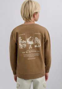 Brauner Pullover mit einem aufgedruckten Design auf der Rückseite, das Berge, Bäume und weißen Text zeigt. Gerippte Bündchen und Saum; lockere Passform.