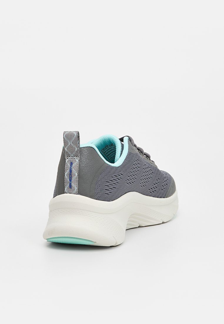 Zapatilla atlética gris con parte superior de punto texturizado, acentos en azul claro y una suela blanca acolchada. Presenta un tirador en el talón con patrón y diseño de cordones.