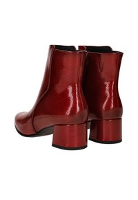 Red patent leather ankle boots with a glossy finish, block heels, and a sleek design, showing stitching and a smooth surface.