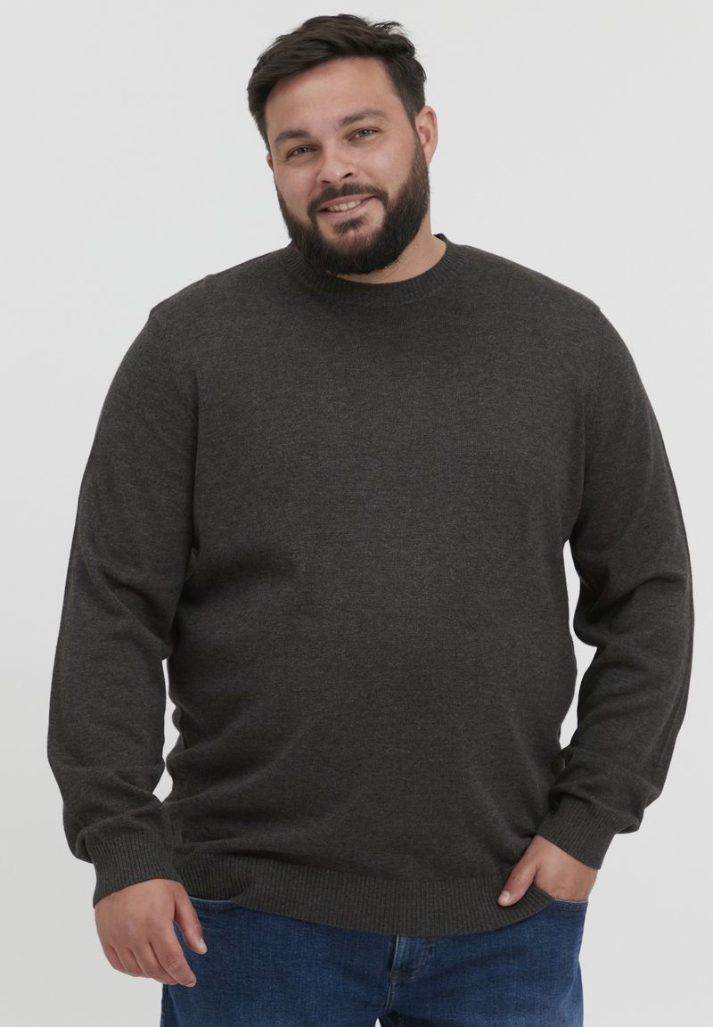 Pull gris foncé avec un col rond, des poignets et un ourlet côtelés. Porté avec un jean bleu, affichant une texture lisse et une coupe décontractée.