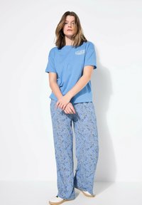 Camiseta de algodón azul claro con un gráfico a la izquierda; combinada con pantalones de pijama sueltos y estampados en un diseño paisley azul y crema.