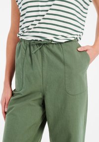 Lichte groene katoenen broek met een losse pasvorm, elastische tailleband, trekkoord en zijzakken, gecombineerd met een wit en groen gestreept shirt.
