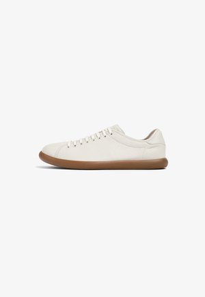 Zapatilla con una parte superior de cuero beige claro, punta redonda y suela plana de goma marrón; cuenta con seis ojales y un diseño de perfil bajo.