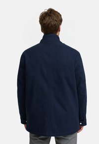 Marineblå, struktureret jakke med lige pasform, stående krave og knapmanchetter, der viser et glat, slidstærkt stof.