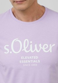 Jasnofioletowy T-shirt z bawełny, z okrągłym dekoltem i białym nadrukiem "s.Oliver" oraz "ELEVATED ESSENTIALS SINCE 1969."