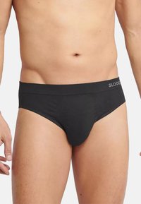 Slip di colore nero, stile brevissimo, realizzato in un tessuto morbido e elasticizzato. Caratterizzato da un elastico in vita liscio con il logo "SLOGG". Design semplice e senza cuciture.