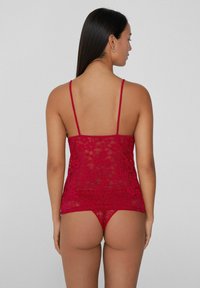 Rotes Spitzen-Dessous-Set mit verstellbaren Trägern, das filigrane Blumenmuster und eine taillierte Passform aufweist. Inklusive passendem Tanga.