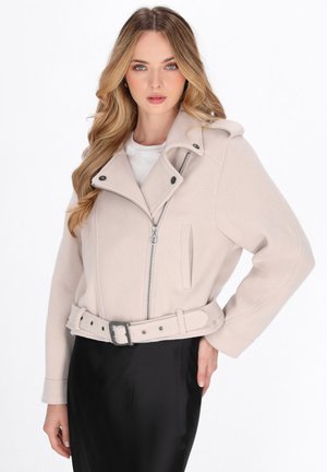 Lichtbeige cropped jack met een gestructureerd ontwerp, ritssluiting, zijzakken en een tailleband. Gemaakt van zachte stof met een textuurafwerking.