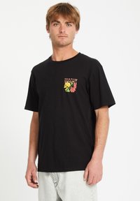 Sort t-shirt med et farverigt blomster- og kraniummotiv på venstre brystområde; korte ærmer, rund hals, fremstillet af bomuld.