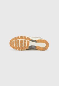 Podeszwa sneakerów Nike ma teksturowaną, brązową gumową podeszwę z prostokątnymi wypustkami, szarymi akcentami oraz wytłoczonym logo w pobliżu pięty.