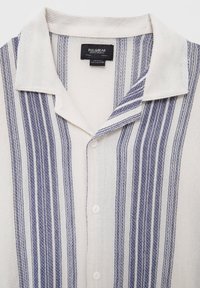 Camicia a maniche corte con bottoni realizzata in tessuto testurizzato. Presenta strisce verticali blu su uno sfondo crema; colletto sovrapposto e bottoni bianchi.