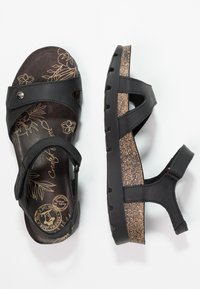 Svarte sandaler med korksåle, med blomstergravering på innersålen, justerbare stropper og en teksturert gummiyttersåle for grep.