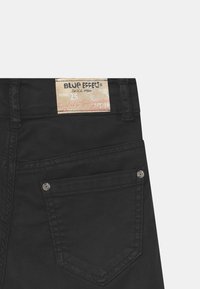 Jeans denim neri con etichetta "Blue Effect" in vita, dotati di due tasche posteriori e dettagli in metallo.