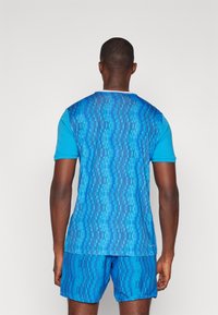 Blue athletic shirt with a textured digital pattern, short sleeves, and a crew neck, paired with matching blue shorts in a similar style.
