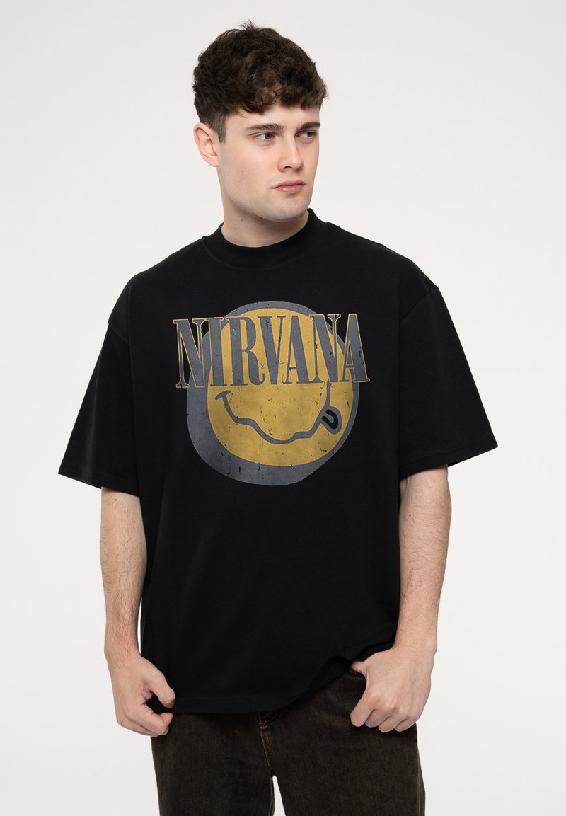 Black t-shirt with oversized fit featuring a distressed yellow smiley face graphic and "NIRVANA" text in gray, made of cotton fabric.